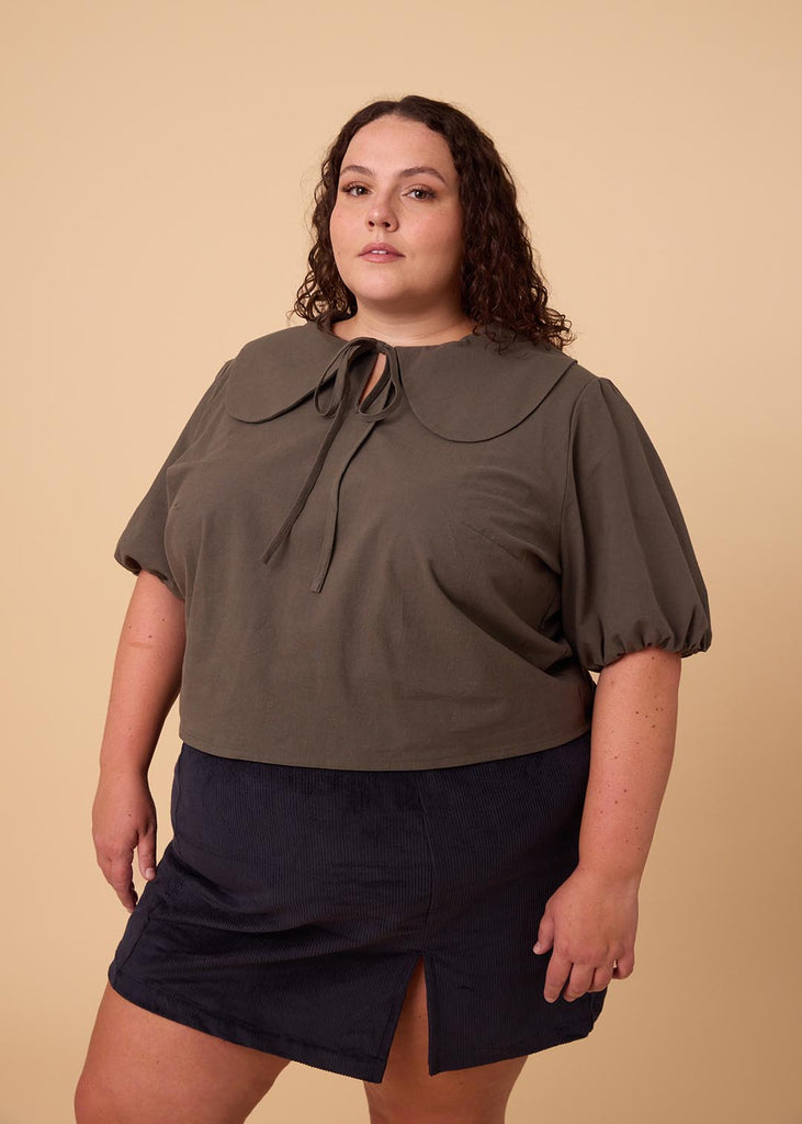 a plus size woman in an olive green blouse with an exaggerated collar