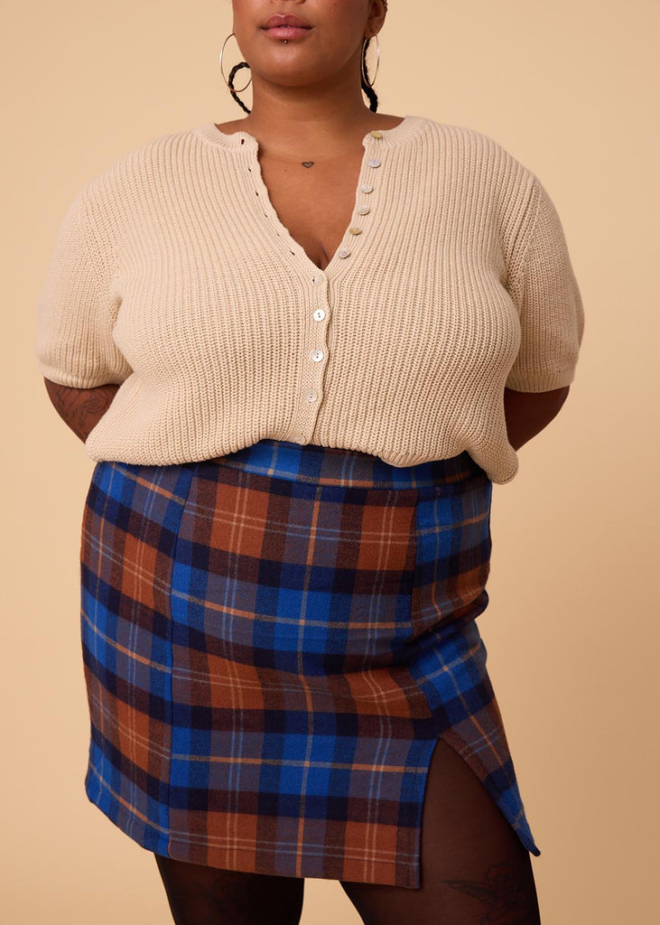 a close up of a plus sized woman wearing a plaid miniskirt