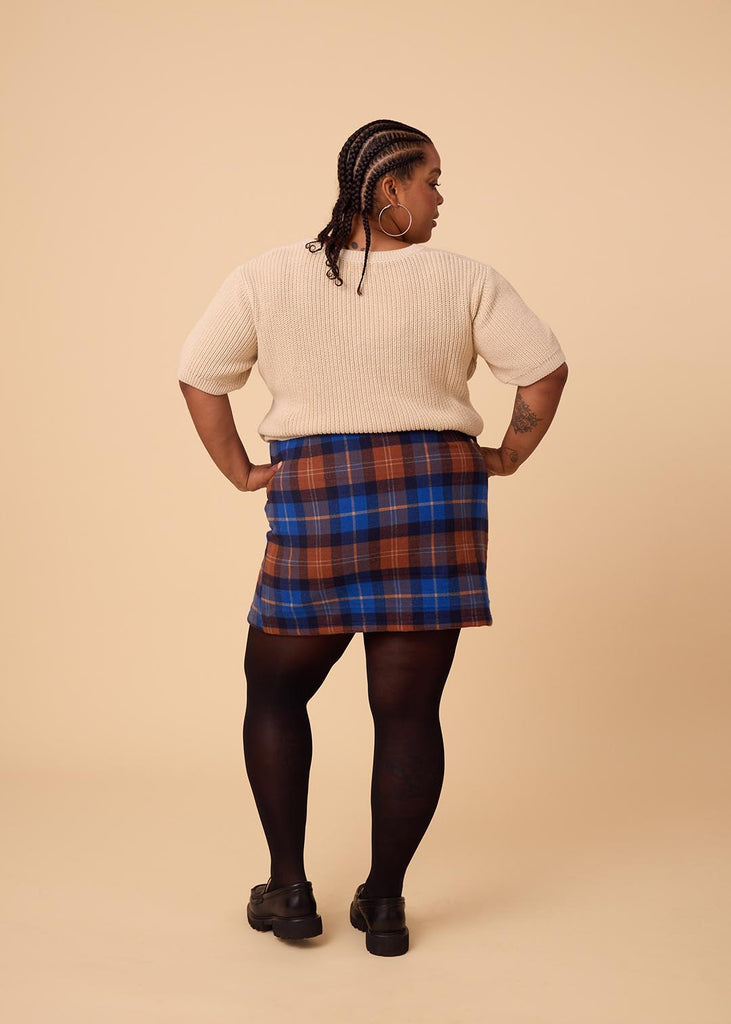 a close up of a plus sized woman wearing a plaid miniskirt