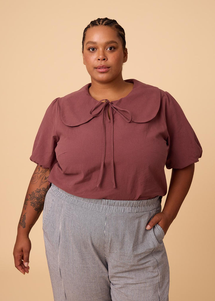 a plus size woman in a plum blouse with an exaggerated collar