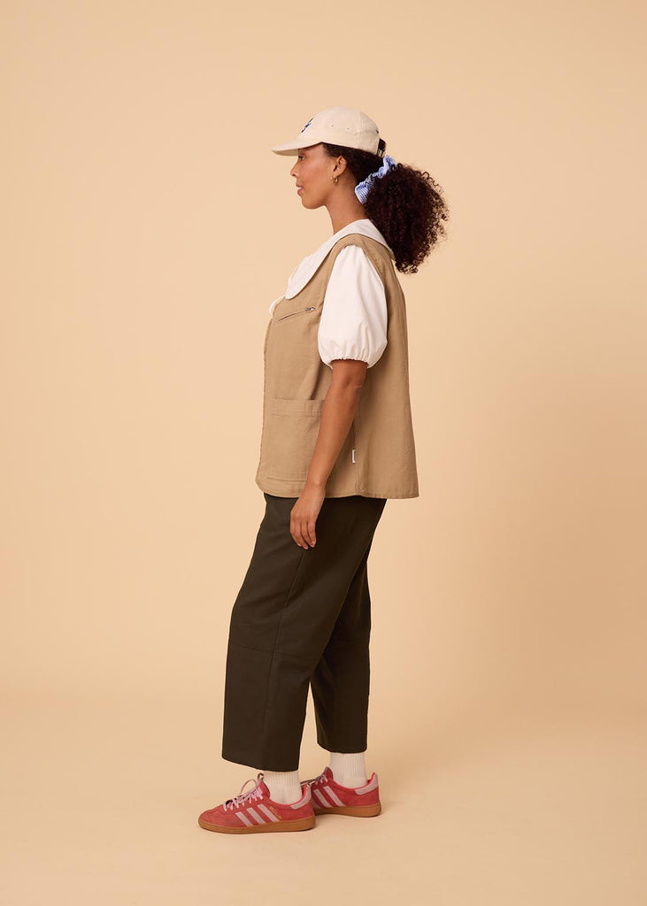 a straight size woman wearing a white blouse with an exaggerated collar worn with an open khaki vest