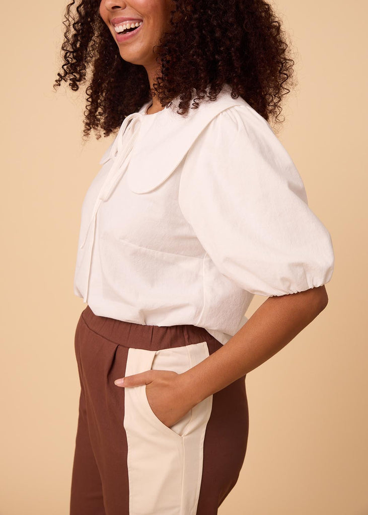 a close up of a straight size woman wearing a white blouse with an exaggerated collar