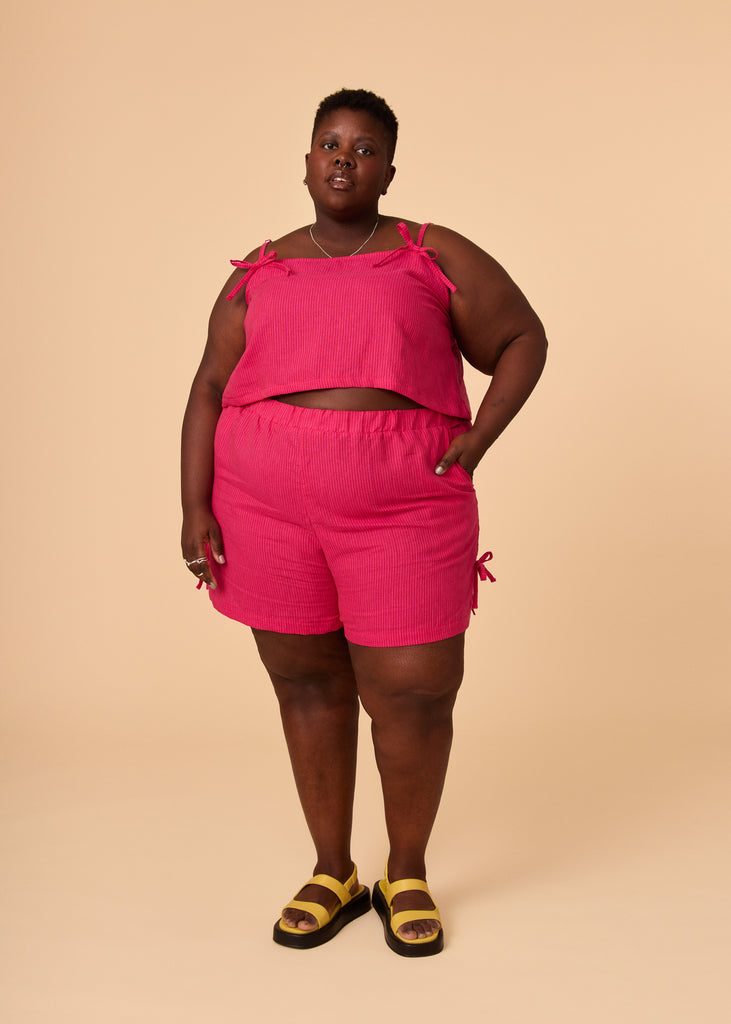 a plus size person wearing matching pink shorts and cropped tank top