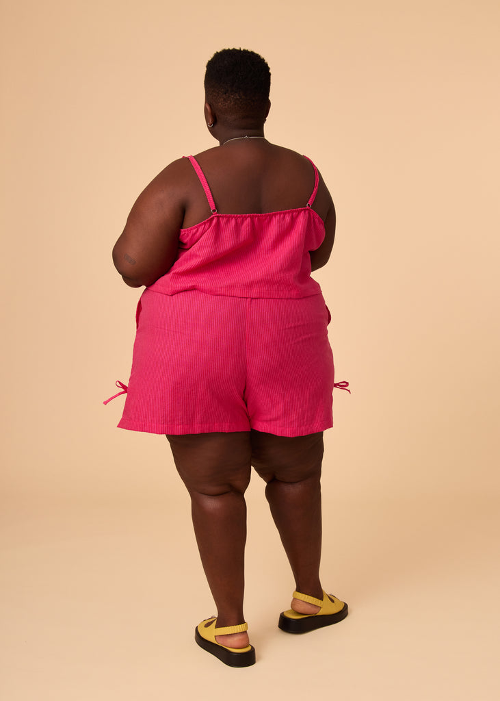 a plus size person wearing matching pink shorts and cropped tank top