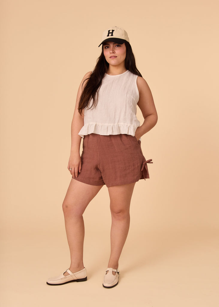 a straight sized woman wearing a white linen tank top and brown shorts