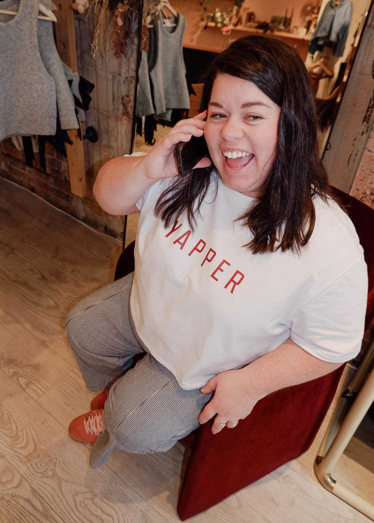 a plus size woman posing with a cell phone, wearing a cropped tee that says "yapper"