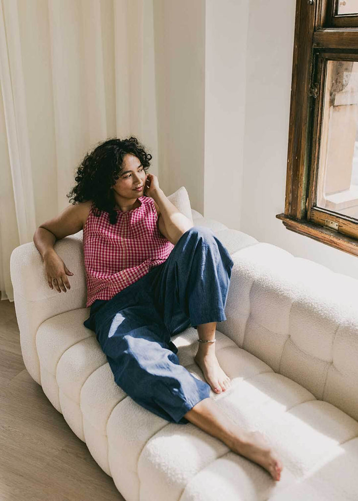 mid size woman lounging on a couch wearing wide leg denim pants