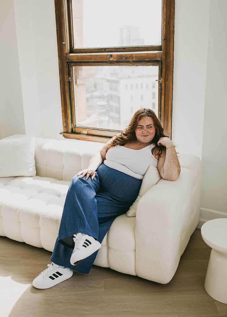 plus size person sitting on a couch wearing wide leg denim pants