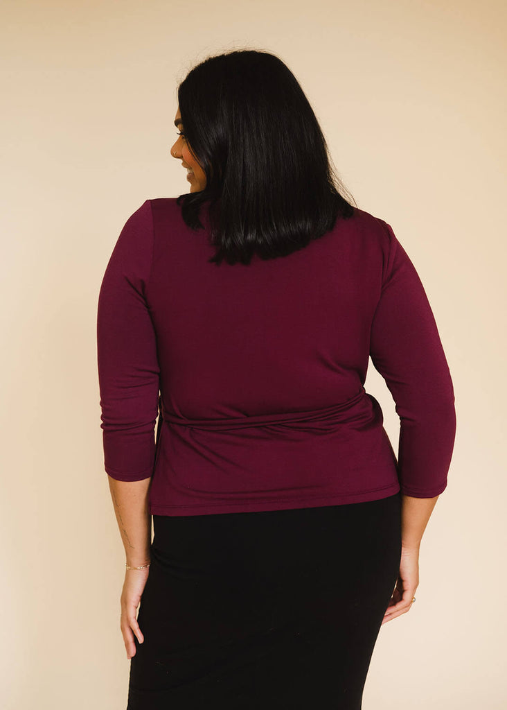 a midsize woman wearing a burgundy wrap top