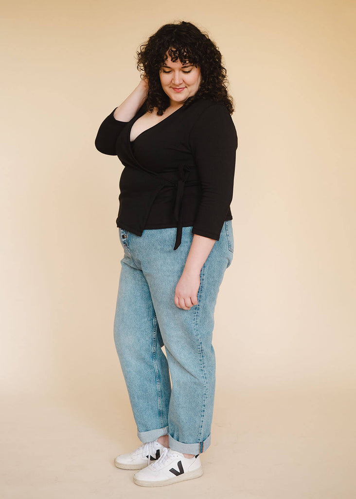 a plus size woman wearing a black wrap top