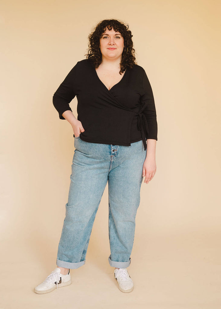 a plus size woman wearing a black wrap top