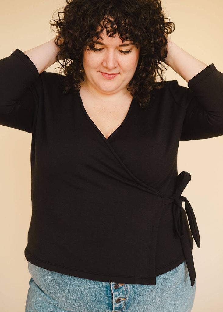 a plus size woman wearing a black wrap top