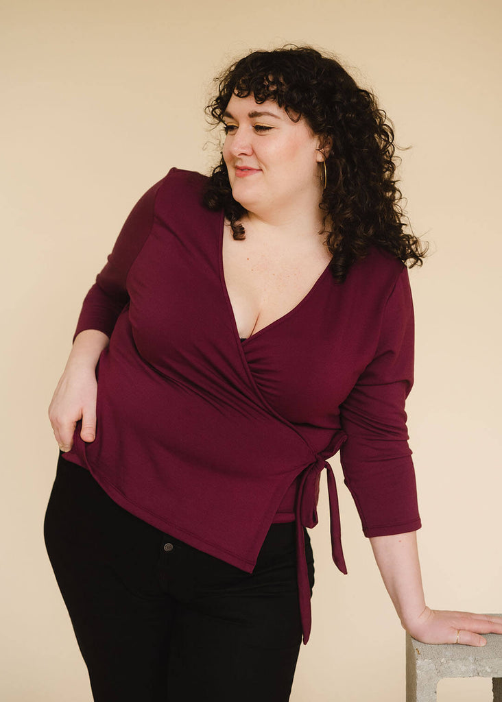 a plus sized woman wearing a burgundy wrap top