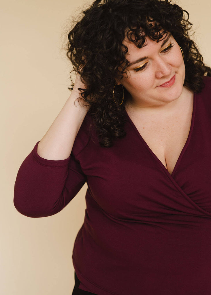 a plus sized woman wearing a burgundy wrap top