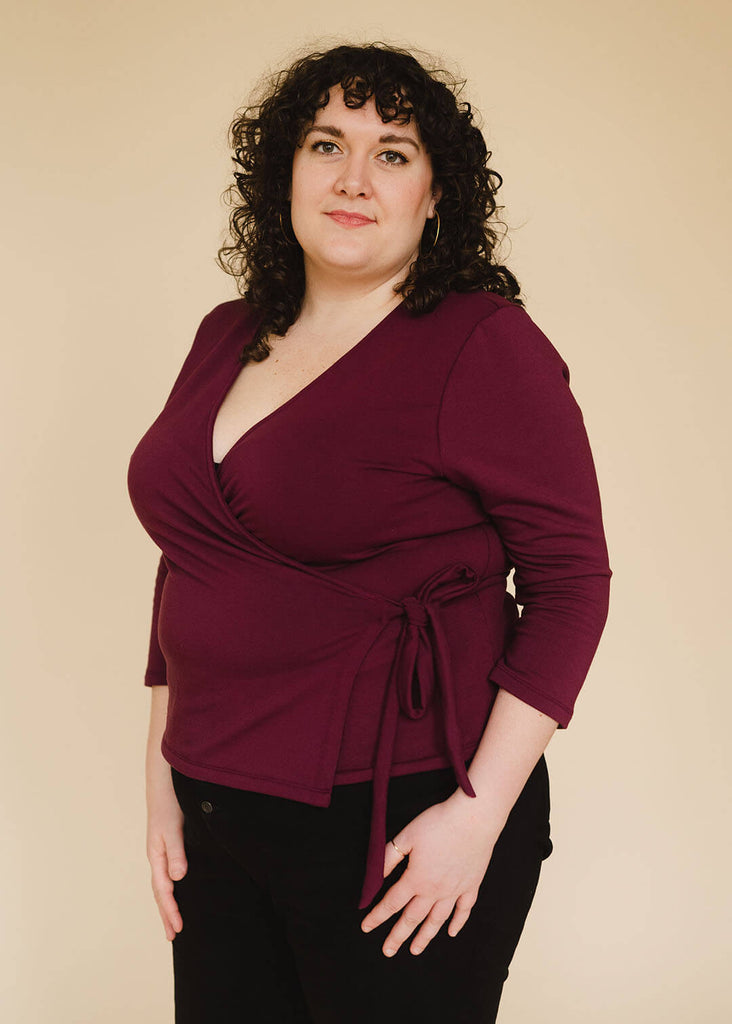 a plus sized woman wearing a burgundy wrap top