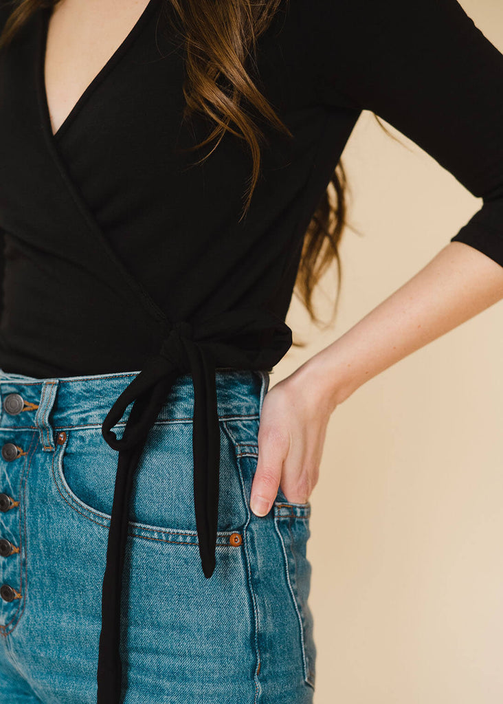 a close up of a straight sized woman wearing a black wrap top